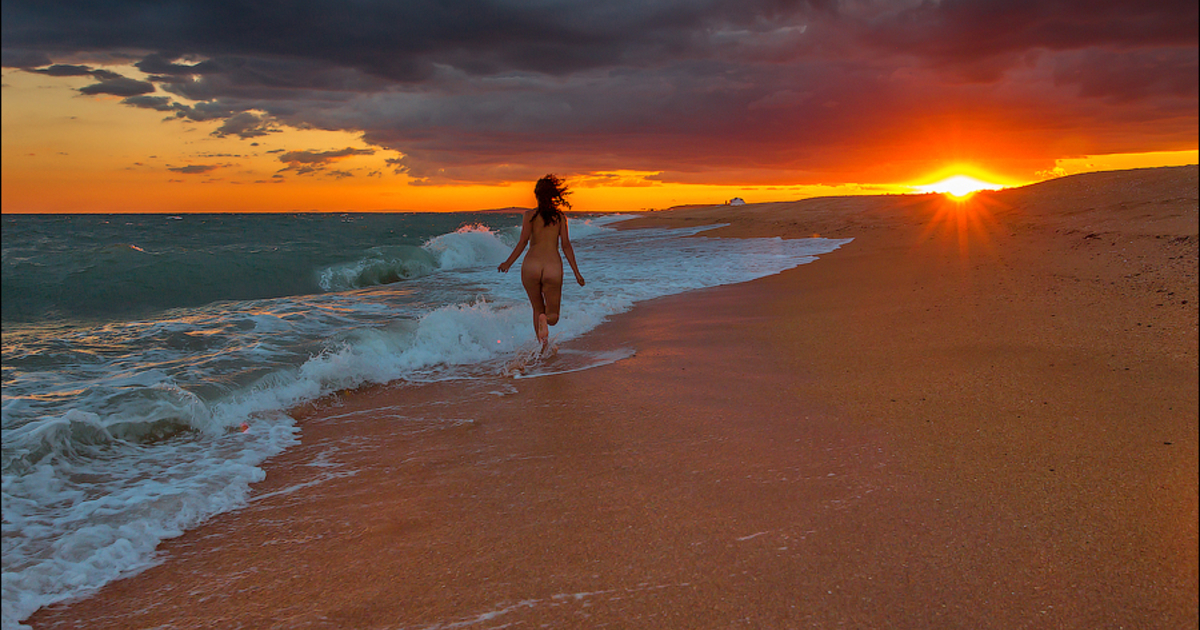 Расскрепощеная красотуля на пляже провожает закат солнца